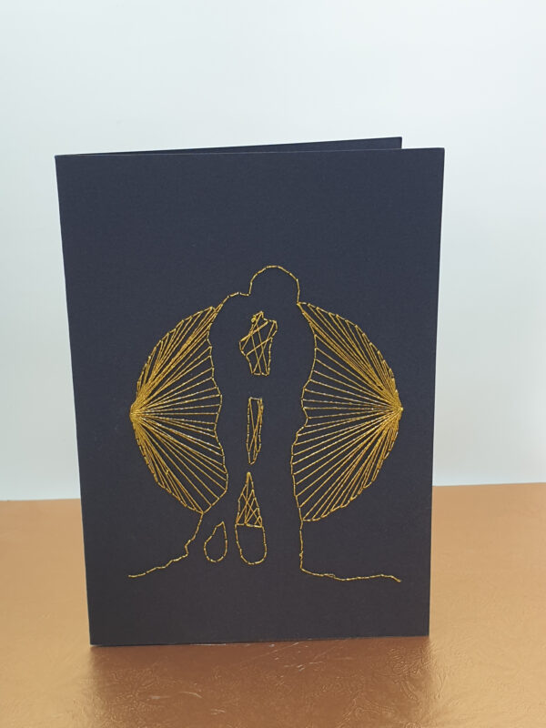 2023 Couple in the Glow of the Moon. This image is of a handcrafted greeting card which depicts a happy couple holding hands in the shadow of a full moon, hand stitched in glittery gold thread, on a black card.